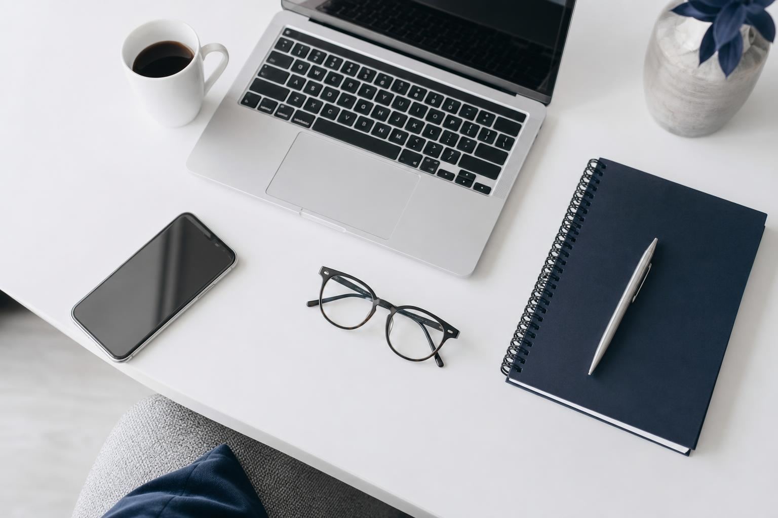 Bureau vu du dessus avec un ordinateur portable, une tasse de café et un carnet de notes